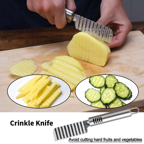 Stainless steel crinkle knife with ridged blade slicing a potato on a cutting board; pineapple and cucumber slices nearby.