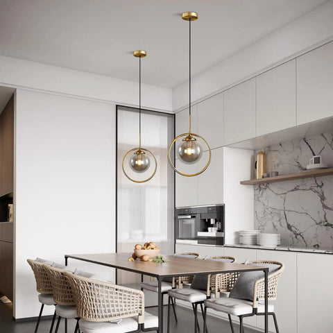 Dope Smoke Gray Glass Globe Pendant Light With Gold Rim in a modern kitchen setting, above dining table for versatile lighting.