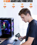 Person using Beastly Mini Air Duster With LED Light 150000 RPM Turbo Blower to clean keyboard near a glowing PC case