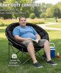 Man relaxing outdoors in XXL Folding Round Camping Chair With Super Cushioned Padded Seat For All Day Comfort Heavy Duty Frame