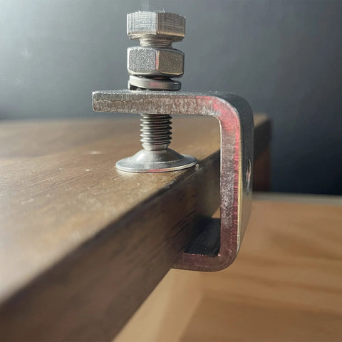 C-clamp woodworking clamp on a wooden board; red metal frame with screw and pad, 1-inch jaw opening