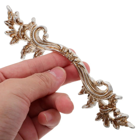 Person holding a Vintage Zinc Alloy Cabinet Handles Set With Antique Silver Finish, showing European style carved detail.