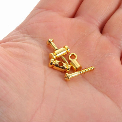 Premium Brass Electric Guitar String Trees Retainers 2 Pairs in hand, golden brass material, used to lock tuner heads down.
