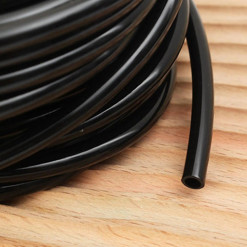 Coiled Heavy Duty Garden Drip Irrigation Hose For Greenhouse And Lawn, black PVC one quarter inch tubing on wooden surface