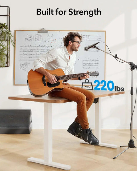 Huanuo Electric Standing Desk Frame With Powerful Brushless Motor For Dual Monitor Riser, man playing guitar, supports loads up to 220 lbs.