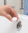 Silicone Bathtub Seal Plug for 30-31mm White 5pcs Round Openings being placed into a bathtub drain by a hand.