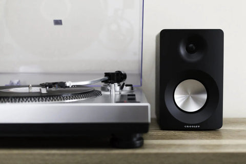 Crosley C100A Silver Belt Drive Turntable With Aluminum Tonearm Pitch Control For 33 And 45 Rpm Vinyl Records and speaker setup.