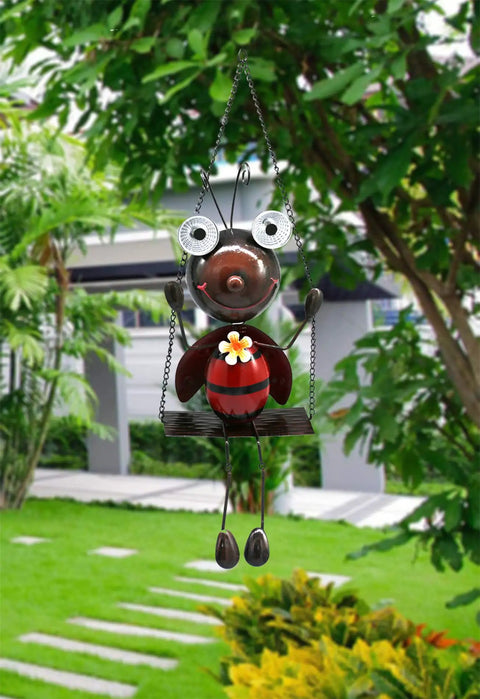Cute ladybug on swing in garden, featuring Solar Powered Ladybug Swing Garden Decor Waterproof Metal Hanging Lights. Daytime view