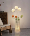 Pastoral LED Floor Lamp With Handwoven Rattan Flower Shade casting warm light beside a wooden chair in a cozy room setting