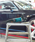 7-Inch Polisher, blue body, rubberized handle, on metal stepladder, with car background for auto detailing use
