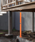 Side view: VEVOR orange steel telescoping floor jack post under wooden deck beam, adjustable height.