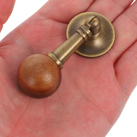 Vintage Cabinet Door Pull Handle In Antique Brass With Black Walnut Wood Round Pendant Knob shown on hand palm