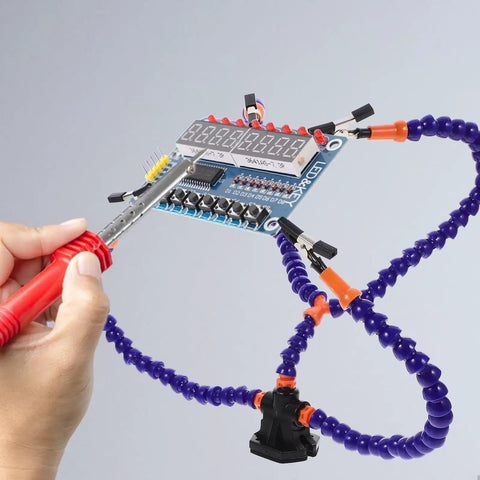Third Hand Soldering Station and Tool Holder Blue in use with clamp holding a PCB board while a hand operates a soldering iron.