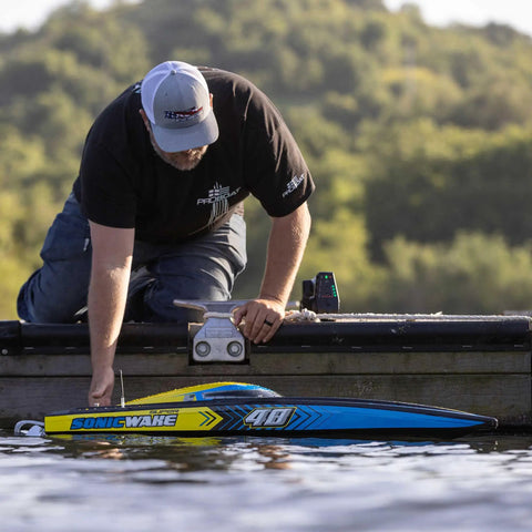 Man preparing Sonicwake RC Boat 48 Inch Self Righting Brushless 8S Ready To Run on dock.