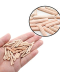 Hand holding 48 pack 4mm by 25mm dowel pins with fluted beveled ends for tight wood joints and shelf support hardwood dowels.
