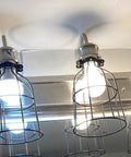 Premium Black Metal Wire Cage Lamp Guard For Ceiling Fans And Pendant Lights Killer Diamond Shape Light Cover With Slick Rust Resistant Coating Set Of Two in use with bulbs.
