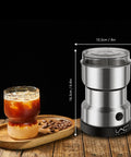 Electric Coffee And Spice Grinder Handheld 150W Quick Grinding With Stainless Steel Blades next to a glass of iced coffee