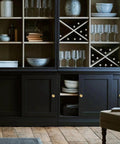 Black cabinet with 4 Pack Solid Brass Finger Pulls For Sliding Doors And Cabinets in brushed gold, showcasing glassware and decor.