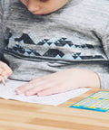 Child using 40 Pack Multiplication Chart Stickers for Students, 4 by 5 inch desk size times table sheets for school.