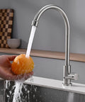 A Total Game Changer For Your Modern Kitchen Or Home Bar With This Dependable Cold Water Only Faucet Finished In Smooth Brushed Nickel And Built Darn Tough From Pure Food Grade 304 Stainless Steel pouring water over an orange.