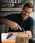 VOTREK orange retractable box cutter knife with ergonomic non-slip grip cutting a cardboard box (front view)