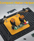 Dual Clamp Soldering Helper Stand With Quick Release Third Hand For Electronics PCB Repair DIY Projects Jewelry Craft No Fuss Soldering Aid Station Adjustable Compact Yellow Black with circuit board on grid mat.