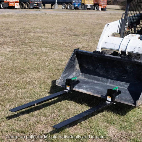 Beefy 60 Inch Clamp On Pallet Forks For Loaders And Skid Steers attached to loader bucket on grass field