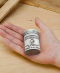 Hand holding 65 ml tin of Micro Crystalline Wax Polish For Furniture, Wood, Leather And Metal That Delivers A Slick Shine