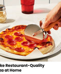 Person using a cutter on a pepperoni pizza made with Indoor Pizza Oven That Makes 12 Inch Pizzas Fast, Reaches Up To 800 Degrees Fahrenheit, Countertop Electric Maker With 5 Presets, Includes Pizza Stone And Peel For Easy Restaurant Quality Pies.