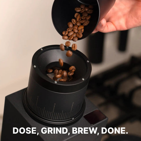 Subscale Digital Dosing Cup With LED Display Sleek Black Scale for Espresso Brewing as coffee beans are poured into grinder.