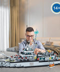 Man building massive 8 in 1 military battleship building set with 31.5 inch navy warship model for boys and adults over 2000 pieces.