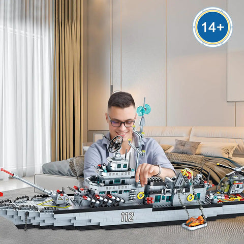 Man building massive 8 in 1 military battleship building set with 31.5 inch navy warship model for boys and adults over 2000 pieces.