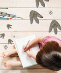 Child drawing on floor with 64 Piece Dinosaur Footprint Floor Decals Peel And Stick Dinosaurs Wall Tracks Stickers visible