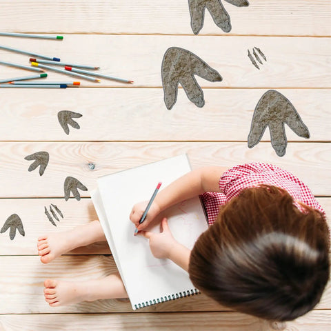 Child drawing on floor with 64 Piece Dinosaur Footprint Floor Decals Peel And Stick Dinosaurs Wall Tracks Stickers visible