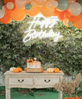 LED Neon Happy Birthday Sign Night Light For Party Backdrops And Bedroom Wall Decor above a decorated table at a party.