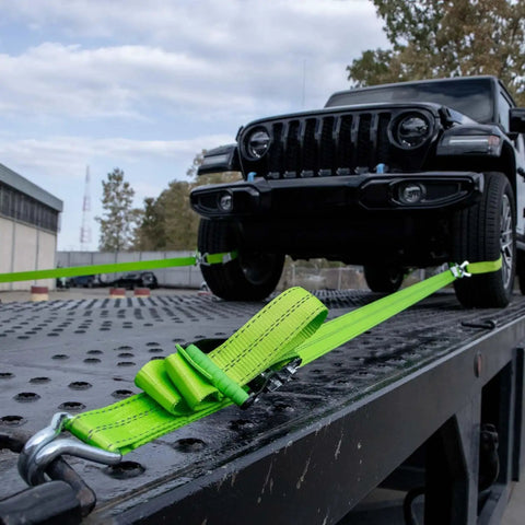 Heavy Duty Axle Tie Down Kit Featuring Hella Bright Neon Green 2 Inch Webbing And Reliable Wire J Hook Ratchet Straps for vehicle securement on flatbed.