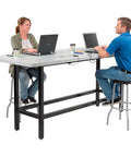 Top Shelf Standing Bar Table With Twelve Built In AC Outlets And Sturdy Footrest Crafted For Cafes Bars And Modern Offices, two people working.