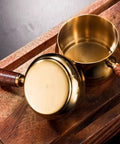 Gold Stainless Steel Espresso Measuring Cup 6 Oz 180 Ml With Wooden Handle And V Shaped Spout On Wooden Surface