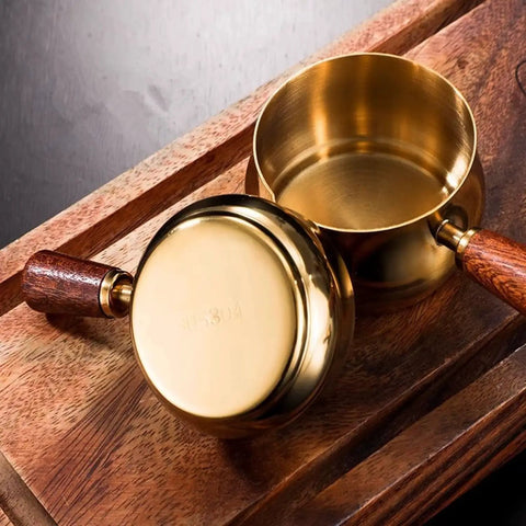 Gold Stainless Steel Espresso Measuring Cup 6 Oz 180 Ml With Wooden Handle And V Shaped Spout On Wooden Surface