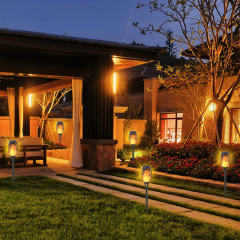 12 Pack Solar Torch Lights With Realistic Flickering Flame, 12 LEDs, IP65 Waterproof Tiki Torches illuminating a garden patio