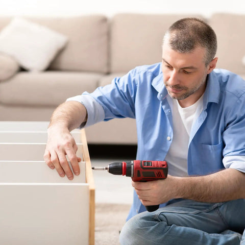 Man using drill for furniture assembly, illustrating practical use of self tapping gutter screws white painted slotted hex washer head size eight by one half inch zinc plated finish includes one quarter inch magnetic hex driver hundred count for DIY gutter install.
