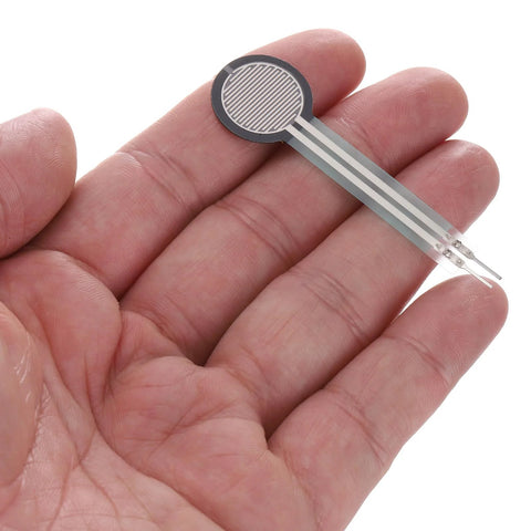 FSR402B thin-film pressure sensor with round gray sensing pad on flexible silver ribbon, held in hand.