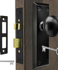 Old School Antique Interior Door Knobs With Mortise Lock Set And Vintage Skeleton Key Handles For Bathroom Bedroom Replacement Hardware. Close-up of the black knob and key.