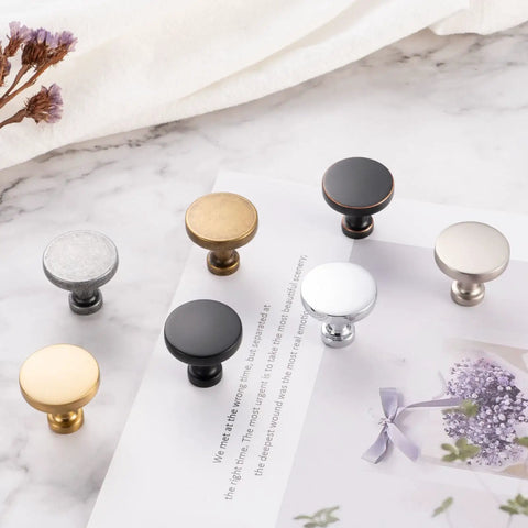 Assorted cabinet knobs on a marble surface, featuring different finishes and styles complementing the Ten Pack Oil Rubbed Bronze Knobs.