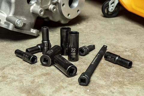 18 Piece Deep Metric Impact Socket Set for One Half Inch Drive, Off Corner Loading to Prevent Rounding, scattered on workshop floor.
