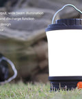CL30R Camping Lantern With 650 Lumens, USB Rechargeable on grass, highlighting its glow and portable design, near a backpack.