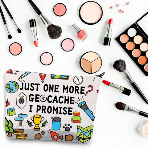 Just One More Geocache I Promise Makeup Bag among cosmetics and brushes, showing outdoor-themed design on canvas.