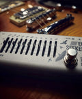 Close-up of 10 Band Graphic EQ Pedal For Guitar And Bass True Bypass Design Compact EQ Seeker with visible sliders and on/off switch.