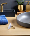 Copper Pop up Bathtub Plug with Bounce Design for Drain Hole beside a blue towel and modern sink fixture.