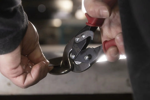 Close-up of Left Cut Offset Aviation Snips 10 Inch Workhorse cutting sheet metal, showcasing heavy duty CR steel and molybdenum blade.